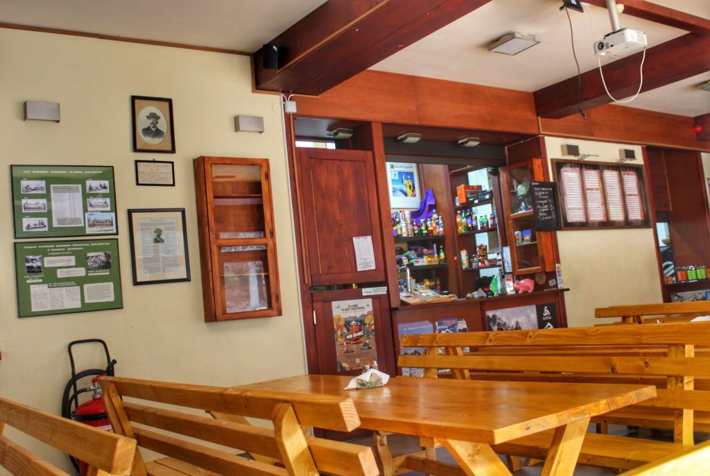 Wnętrze schroniska Markowe Szczawiny, drewniane stoły z ławkami, bufet