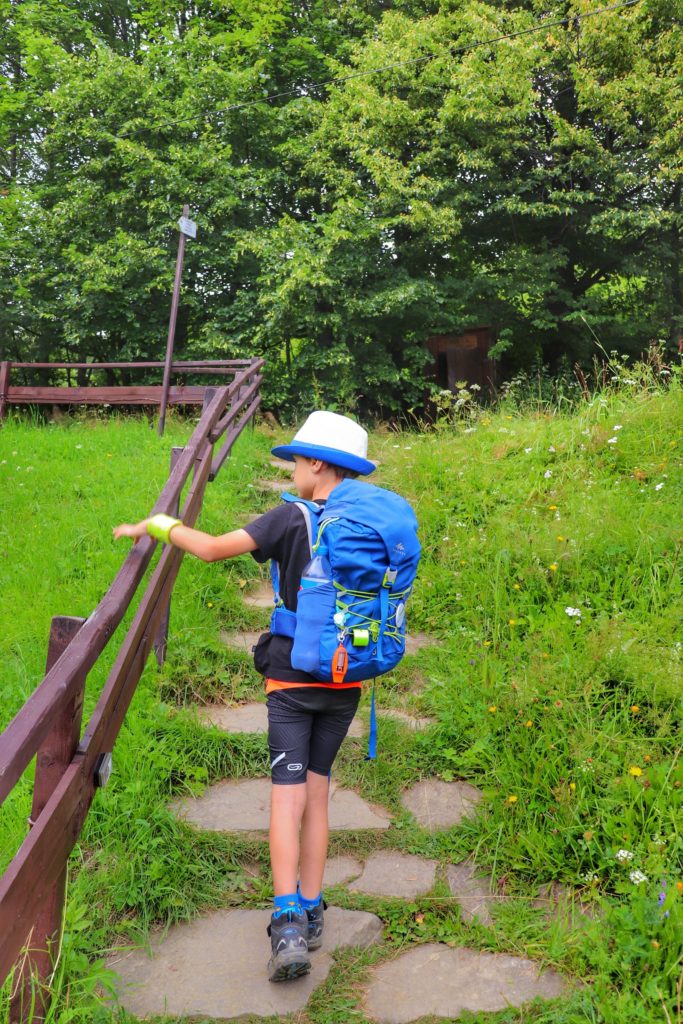 Dziecko wychodzące pod górę, chłopiec trzyma się drewnianej barierki