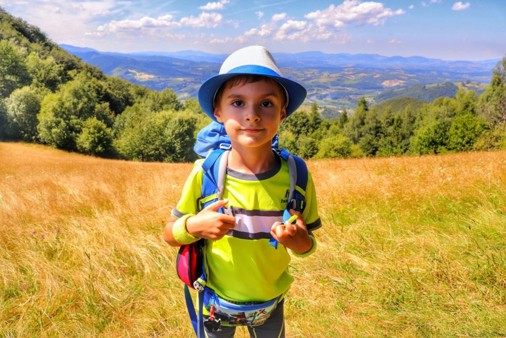 Mały turysta, dziecko w kapeluszu, z plecakiem turystycznym na Polanie Kretówki