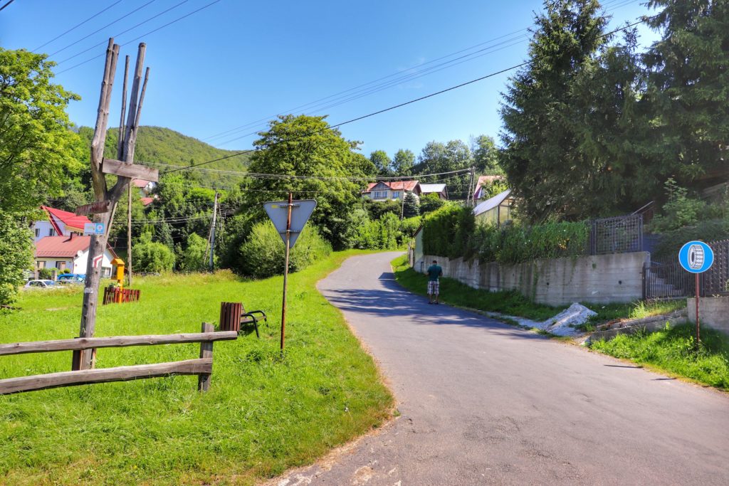 Miejsce skrętu w prawo czerwonego szlaku turystycznego w miejscowości Rytro na ulicy Sucha Struga, asfaltowa droga prowadząca między domami