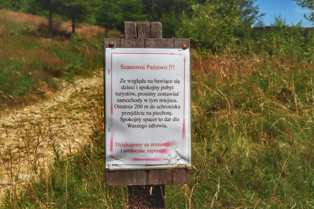 Tabliczka z prośbą do turystów podróżujących samochodem do Schroniska Cyrla o zostawianie samochodów 200 metrów od budynku schroniska