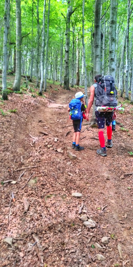 Turysta z dzieckiem idący stromo w górę leśną drogą w kierunku szczytu Makowica