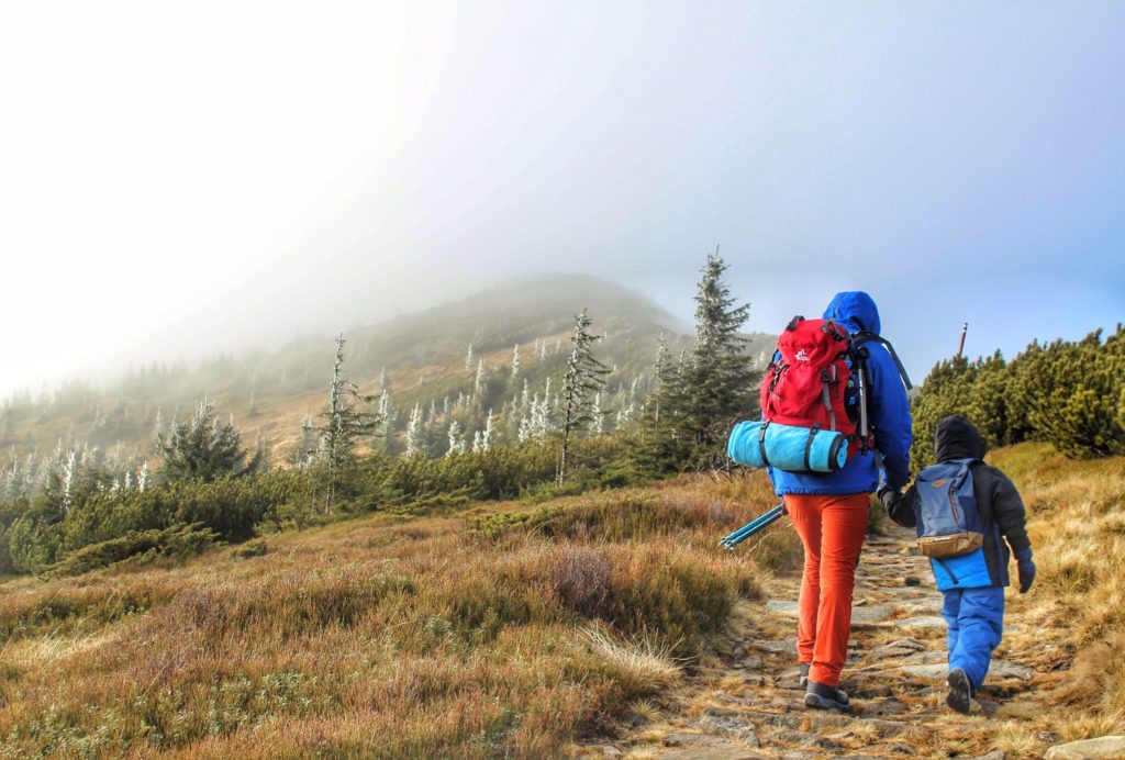 Turysta z dzieckiem idący w stronę szczytu Mała Babia Góra, mgła, zmrożone drzewa