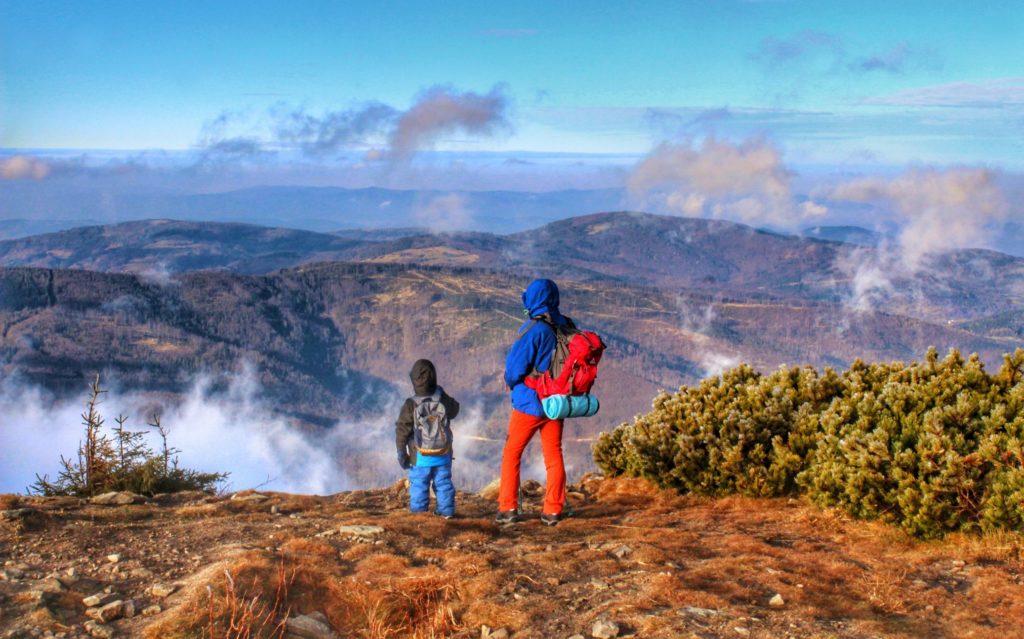 Turysta z dzieckiem podziwiający krajobraz górski rozciągający się ze szczytu Małej Babiej Góry