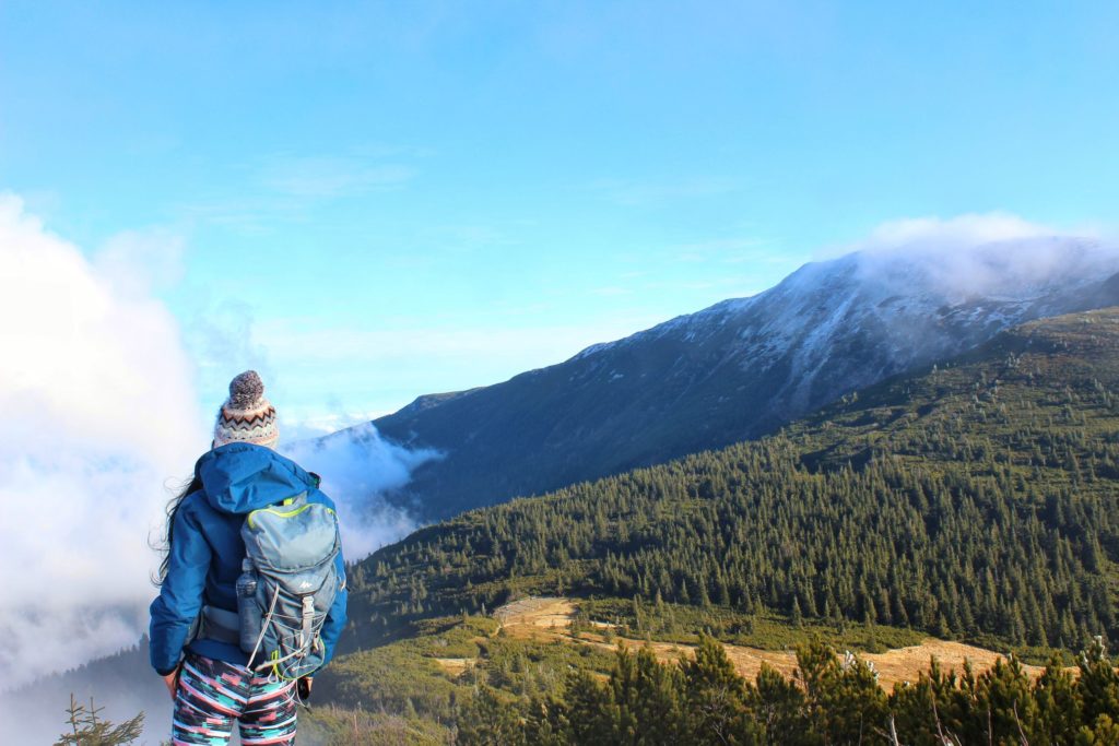 Turystka podziwiająca ośnieżone pasmo Babiej Góry, nad którym tańczą chmury