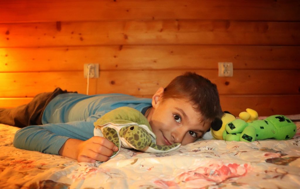 Uśmiechnięte dziecko leżące na łóżku w schronisku CYRLA