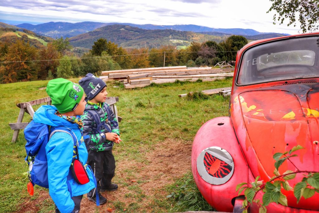 Dzieci podziwiające czerwonego garbusa na Trzech Kopcach Wiślańskich, w tle widok na Beskidy