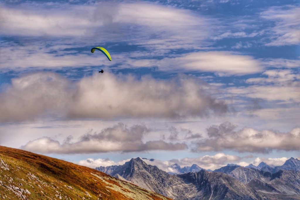 Paralotniarz latający nad Tatrami sfotografowany ze szczytu Ciemniak