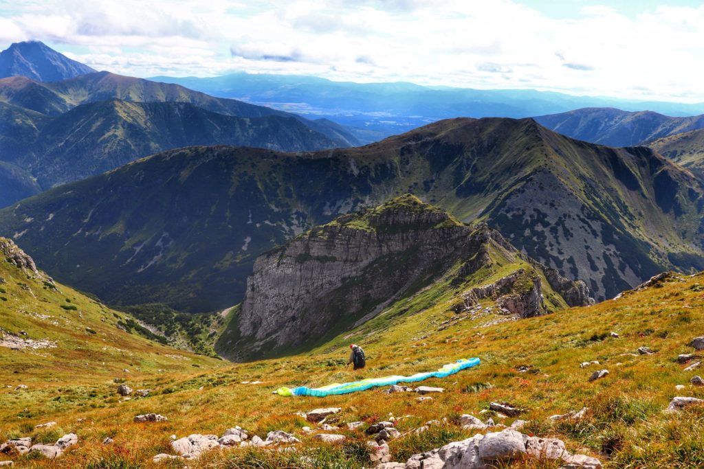 Paralotniarz przygotowujący się do startu, szczyt Ciemniak, widok na Tatry