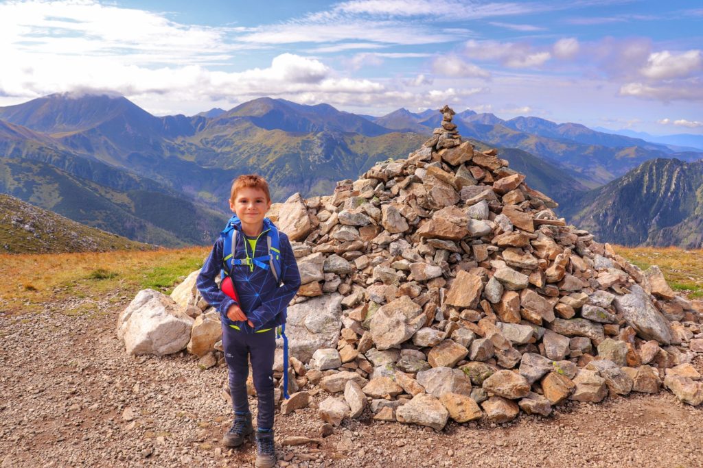 Twarda Kopa, dziecko stojące obok stosu kamieni, w tle widok na Tatry