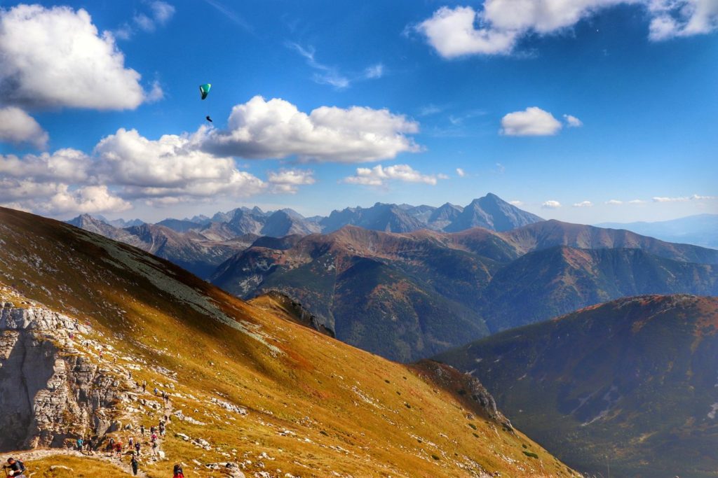 Widok z Ciemniaka w stronę Krzesanicy, paralotniarz nad tatrzańskimi szczytami, jesień