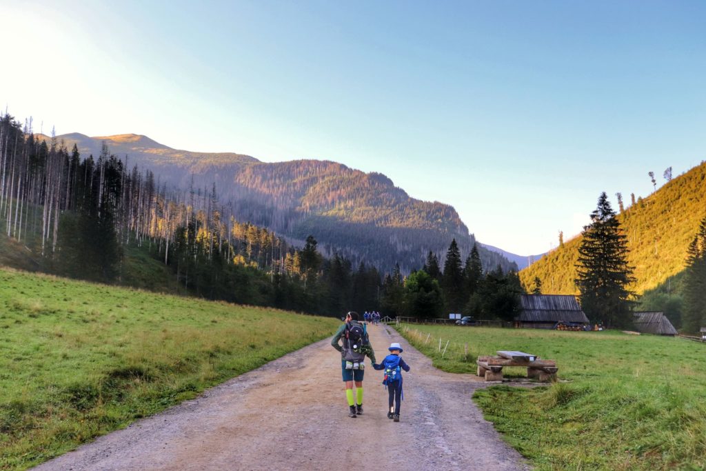 Wrześniowy poranek, turysta z dzieckiem wędrujący szeroką drogą, Dolina Kościeliska