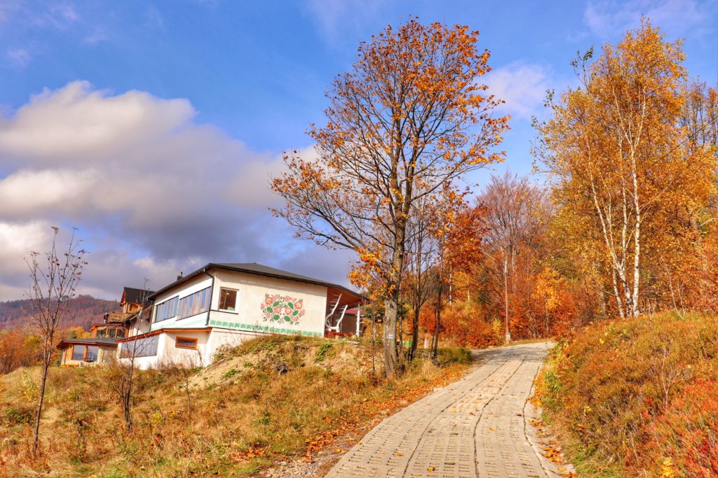 Betonowa droga w Szczyrku na niebieskim szlaku na Klimczok, po prawej stronie biały budynek, piękny, jesienny dzień