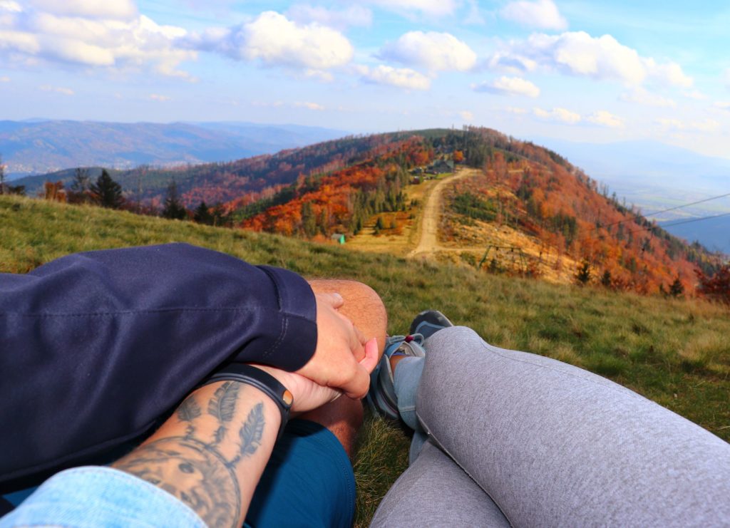 Para odpoczywająca na szczycie Klimczok, trzymająca się za ręce, podziwiająca górski krajobraz