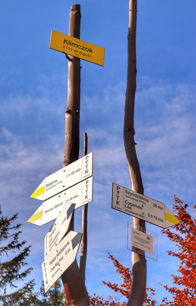 Słup z drogowskazami na szczycie Klimczok (Beskid Śląski), żółta tabliczka z napisem Klimczok 1117 metrów nad poziomem morza, jesień