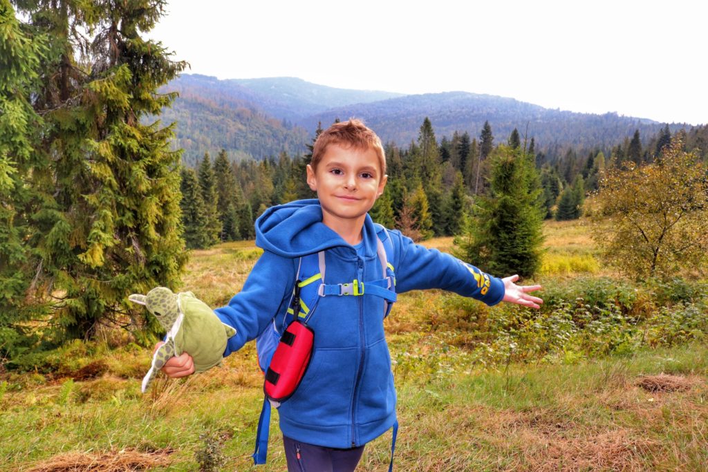 Szczęśliwe dziecko na polanie w Gorcach - szlak zielony, w tle krajobraz górski