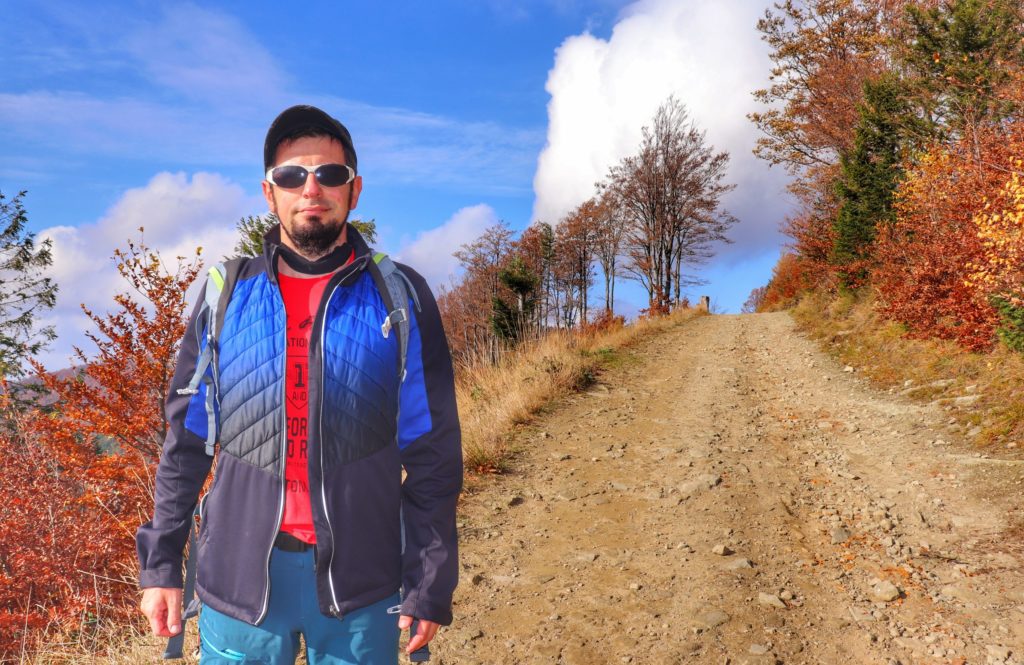 Turysta na zielonym szlaku na Klimczok, w tle pnąca sie w górę droga, jesienna sceneria