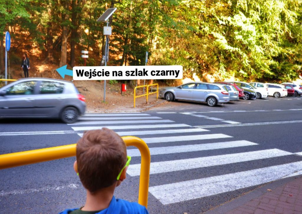 Ulica Jeleniogórska w Szklarskiej Porębie, parking przy czarnym szlaku, przejście dla pieszych przy którym stoi dziecko