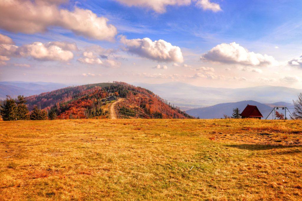 Widok rozciągający się ze szczytu Klimczok w Beskidzie Śląskim, widoczny budynek schroniska na Klimczoku oraz Beskid