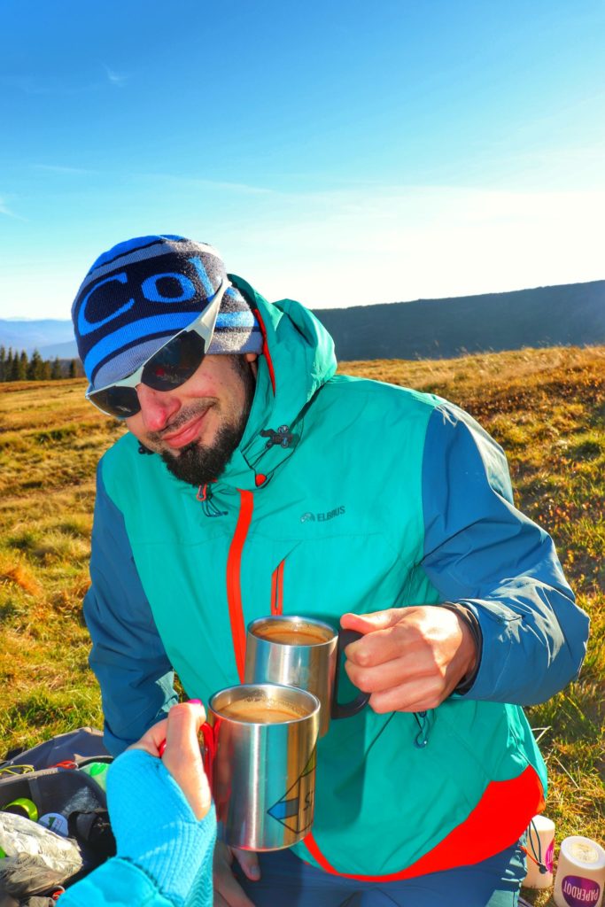 Zadowolony turysta na Hali Baraniej trzymający kubek z kawą