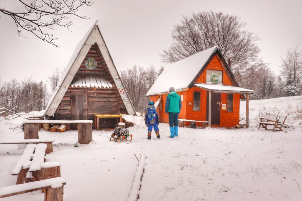 Drewniane chatki na Studenckiej Bazie Namiotowej Przysłop Potócki należące do Oddziału Uczelnianego PTTK z Gliwic, turysta z dzieckiem, zima
