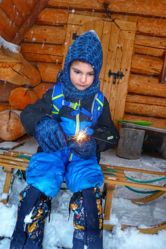 Dziecko siedzące na drewnianych sankach przy chacie na Przełęczy Przysłop Potócki