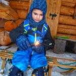 Dziecko siedzące na drewnianych sankach przy chacie na Przełęczy Przysłop Potócki