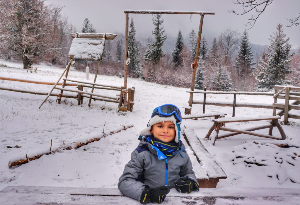 Dziecko siedzące przy zasypanym przez śnieg drewnianym stole, okolice bazy namiotowej - Przysłop Potócki