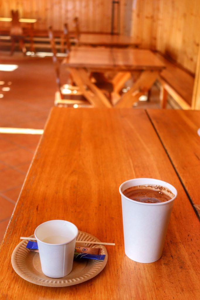 Kubek z kawą oraz kubeczek z mlekiem, drewniany stół, jadalnia w schronisku pod Łabskim Szczytem