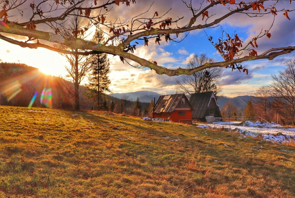Studencka baza namiotowa Przysłop Potócki oświetlona przez popołudniowe słońce, w oddali krajobraz górski, resztki śniegu