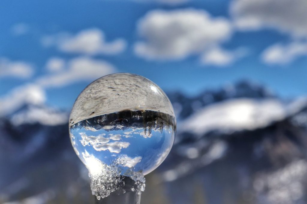 Szklana kula, w której odbijają się zaśnieżone tatrzańskie szczyty, zdjęcie zrobione na Rusinowej Polanie zimą