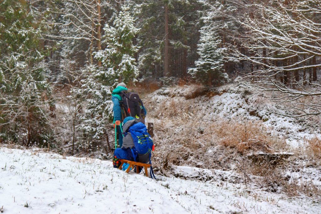 Turysta ciągnący dziecko na sankach, zima w Beskidzie Żywieckim