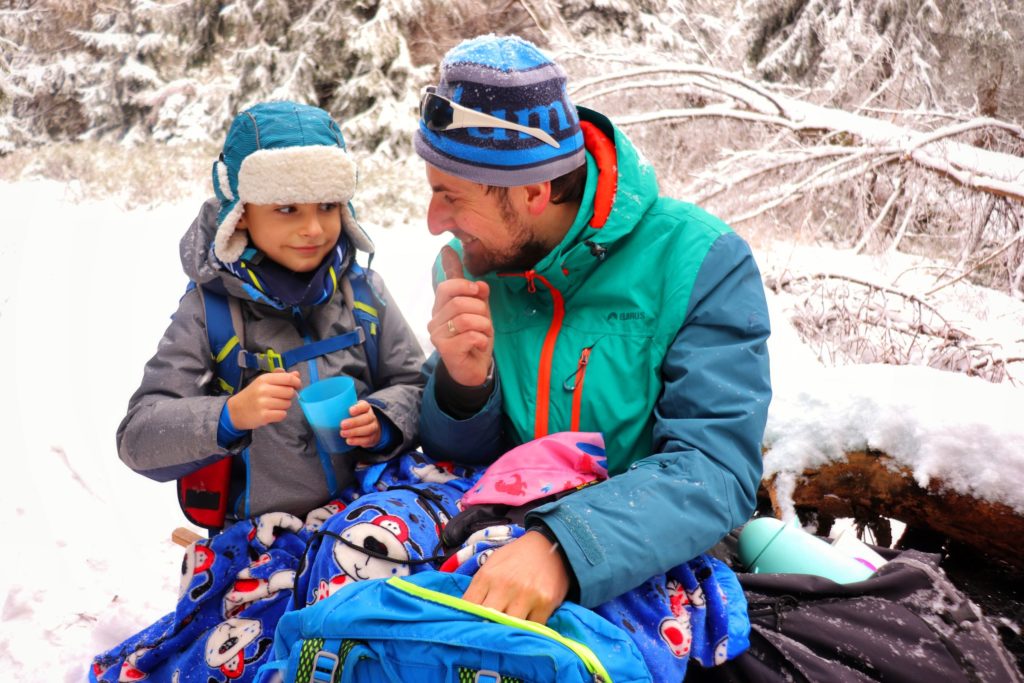 Turysta z dzieckiem odpoczywający na szczycie - Muńcuł, zima