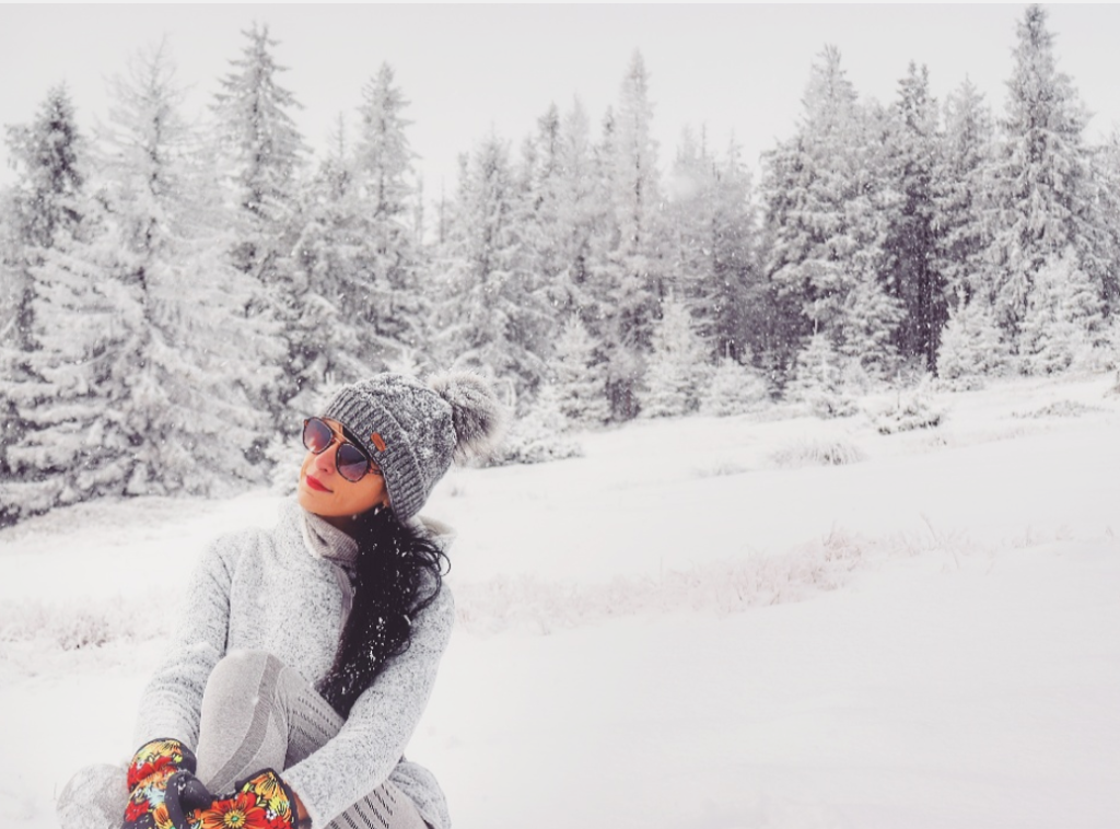 Turystka siedząca na śniegu, w tle ośnieżone drzewa, Beskid Żywiecki