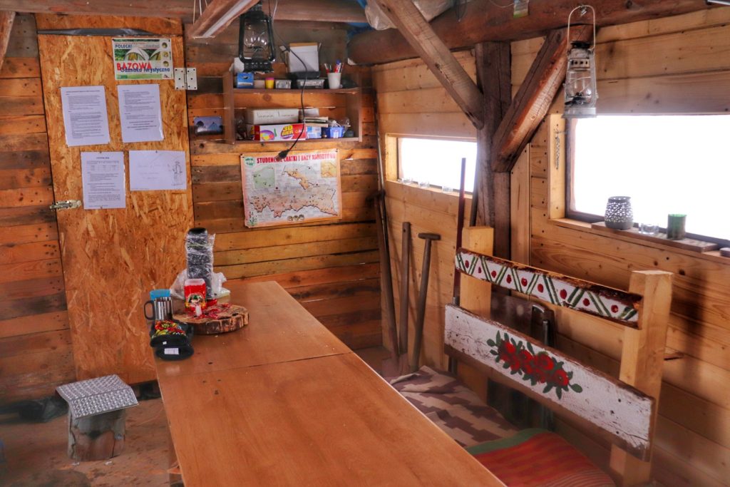 Wnętrze drewnianej chatki na Studenckiej Bazie Namiotowej na Przełęczy Przysłop Potócki, ławka, stół
