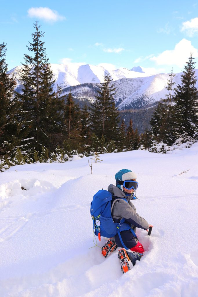 Dziecko bawiące się w głębokim śniegu, w tle ośnieżone, tatrzańskie szczyty