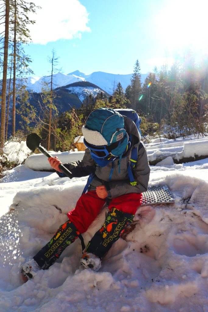 Dziecko bawiące się łopatką w śniegu, zima w Tatrach, słoneczny dzień