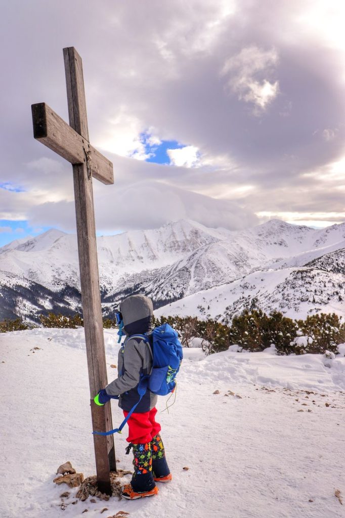 Dziecko przy drewnianym krzyżu na szczycie Grześ, zima, pokryte śniegiem Tatry