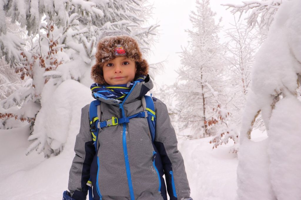 Dziecko, zasypane przez śnieg drzewa, leśna ścieżka