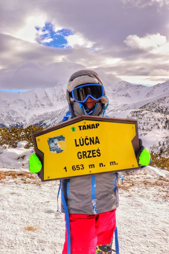 Mały turysta, dziecko na szczycie Grześ zimą, chłopiec trzyma w rękach żółtą tabliczkę z napisem Grześ