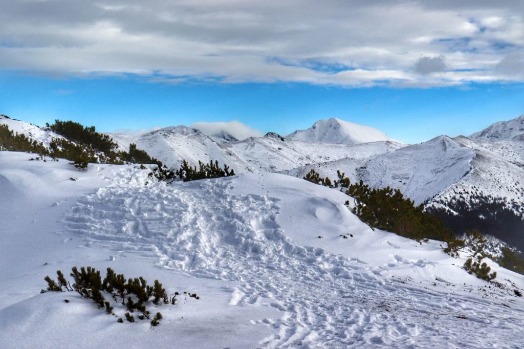 Szczyt Grześ zimą, tatrzańskie szczyty pokryte białym puchem, niebieskie niebo, białe chmury