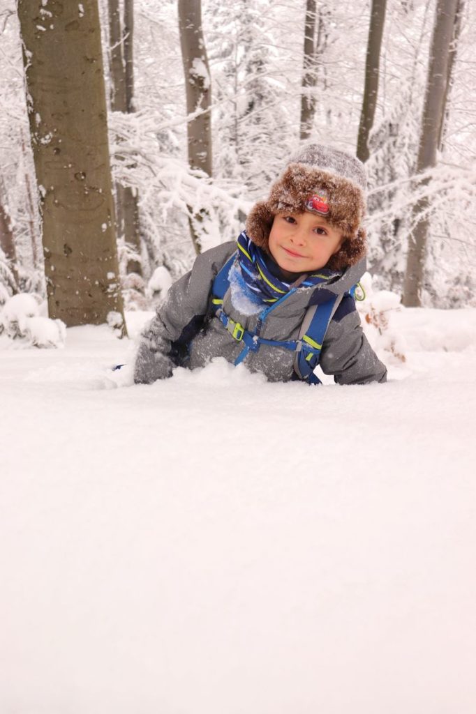 Szczęśliwe dziecko bawiące się w śniegu, las