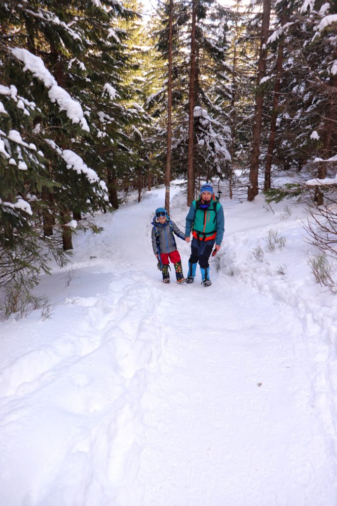 Tatrzański las zimą, mężczyzna z synem, ośnieżona ścieżka oraz drzewa