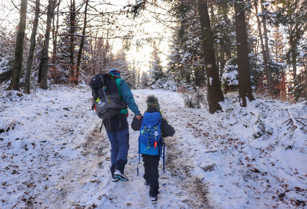 Turysta z dzieckiem, strome, zaśnieżone podejście na żółtym szlaku na Rogacz