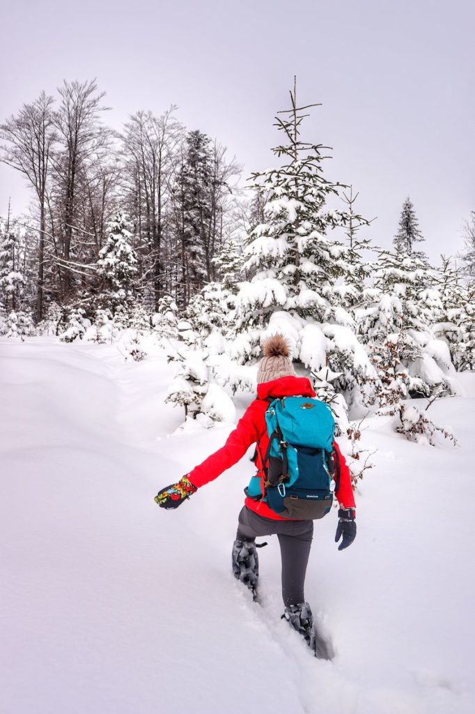 Turystka idąca w głębokim śniegu w stronę Hali Baraniej