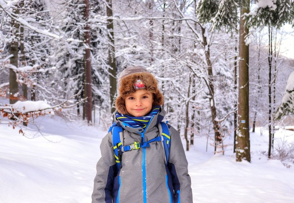 Uśmiechnięte dziecko na niebieskim szlaku w Beskidzie Małym, zima, zaśnieżone drzewa