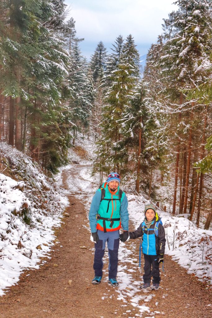 Uśmiechnięty turysta z synem, szeroka droga w Beskidzie Małym, zaśnieżone drzewa