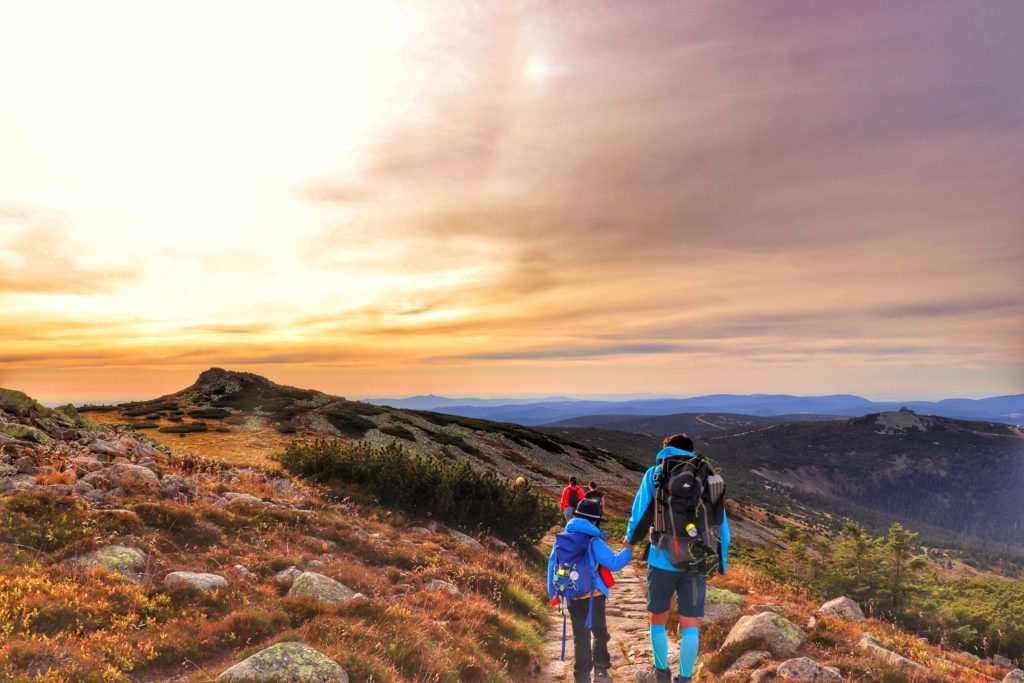 Zachód słońca na niebieskim szlaku w Karkonoszach, turysta z dzieckiem schodzący w stronę schroniska pod Łabskim Szczytem, widok w stronę Szrenicy