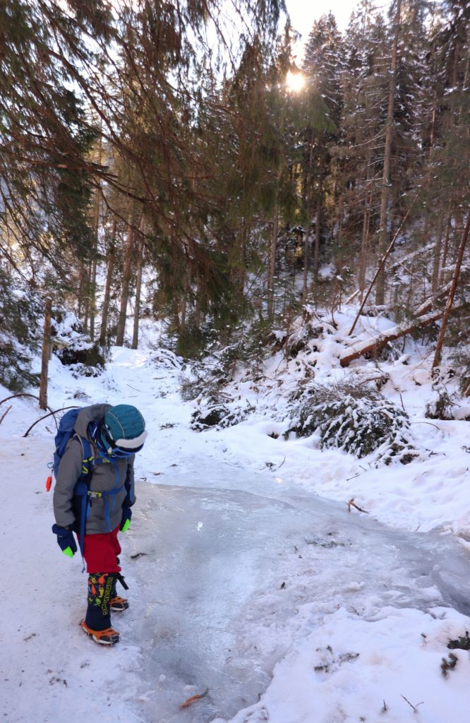 Zadowolone dziecko na oblodzonym szlaku żółtym idącym drogą leśną ze schroniska w Dolinie Chochołowskiej na szczyt Grześ