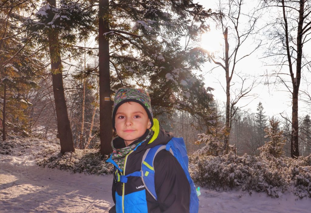 Zadowolone dziecko na żółtym szlaku idącym na szczyt Rogacz, zimowa sceneria, słoneczny, styczniowy dzień